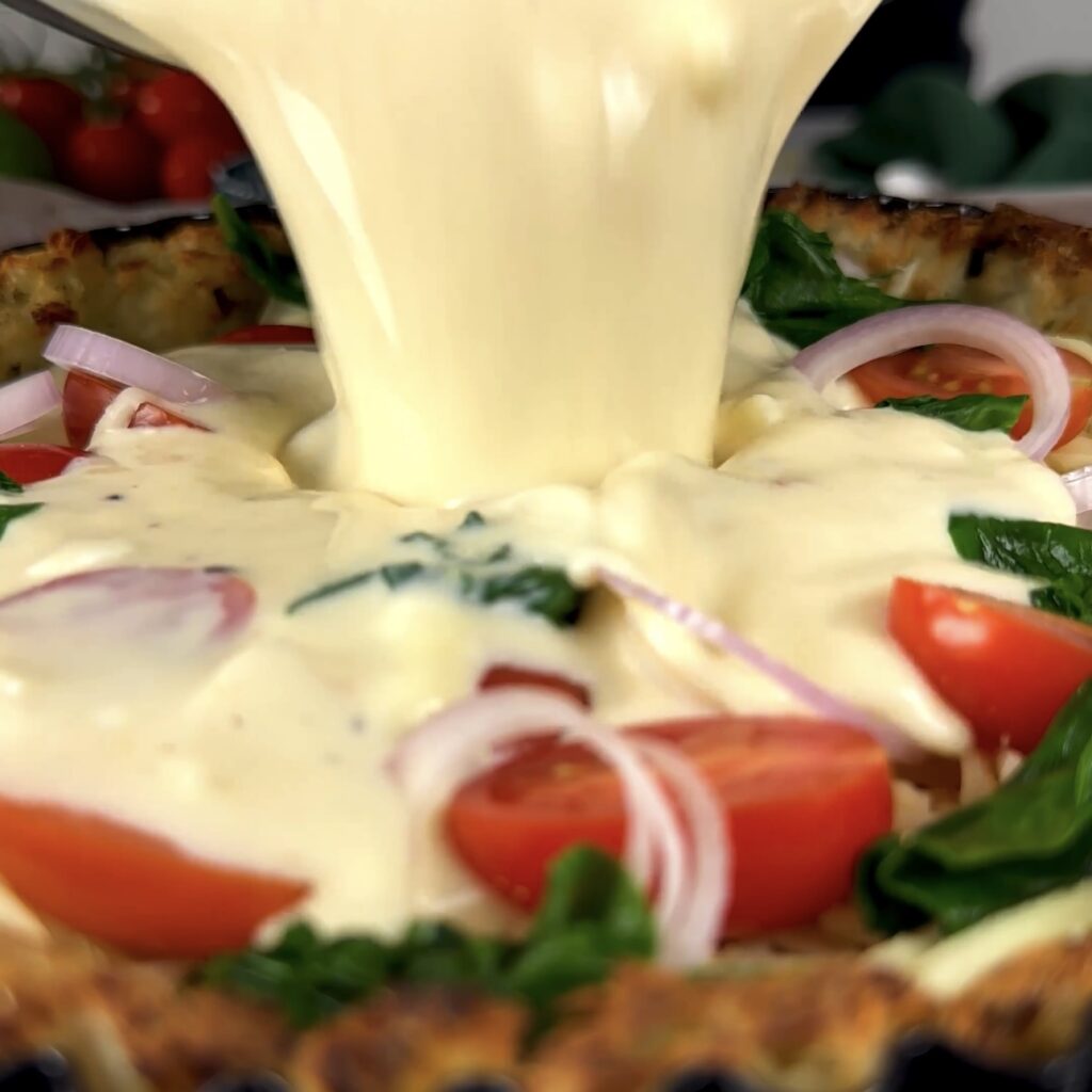 Pouring egg mixture over assembled potato crust and vegetables