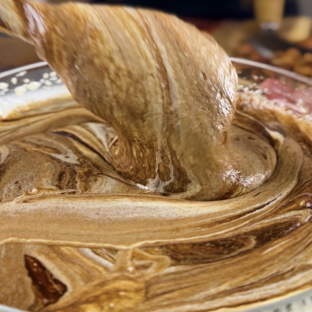 Mixing melted chocolate with egg mixture in a bowl