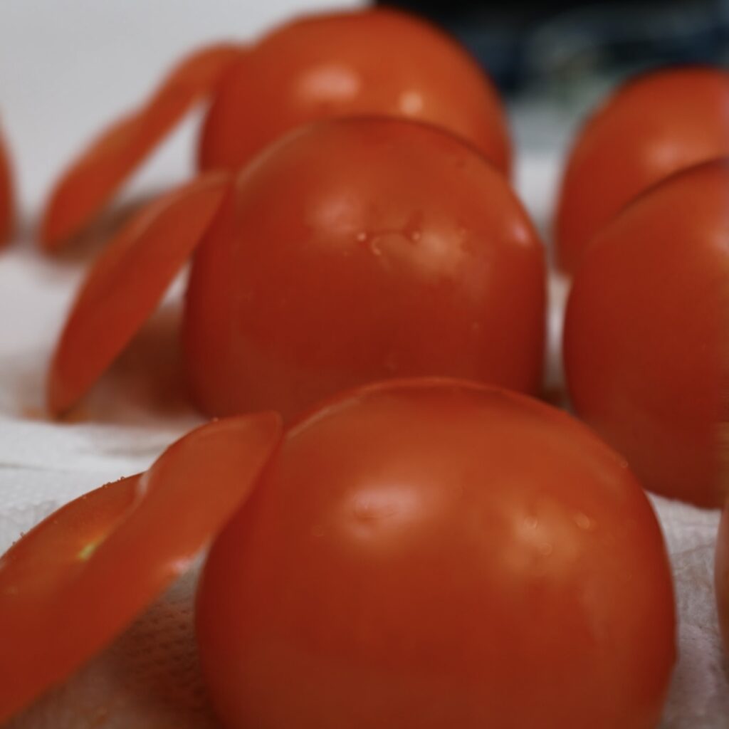 Tomatoes draining upside down on a paper towel.