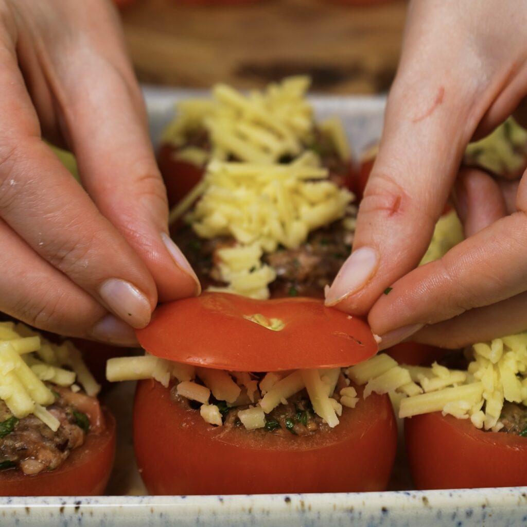 Assembling stuffed tomatoes in a baking dish.