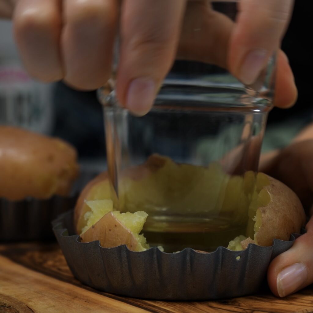 Crushing potatoes directly into mini tart tins.