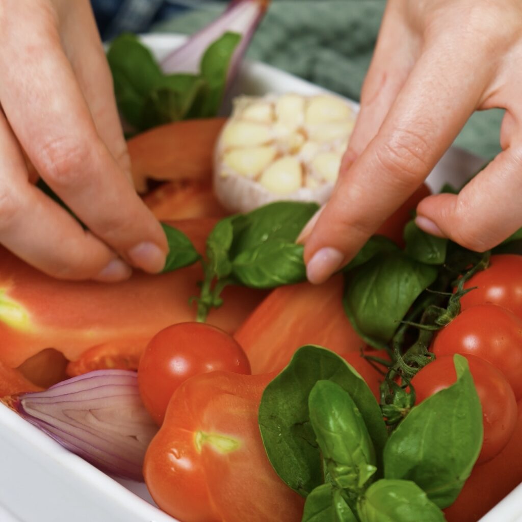 Tomatoes, shallots, garlic, and basil arranged in a baking dish.