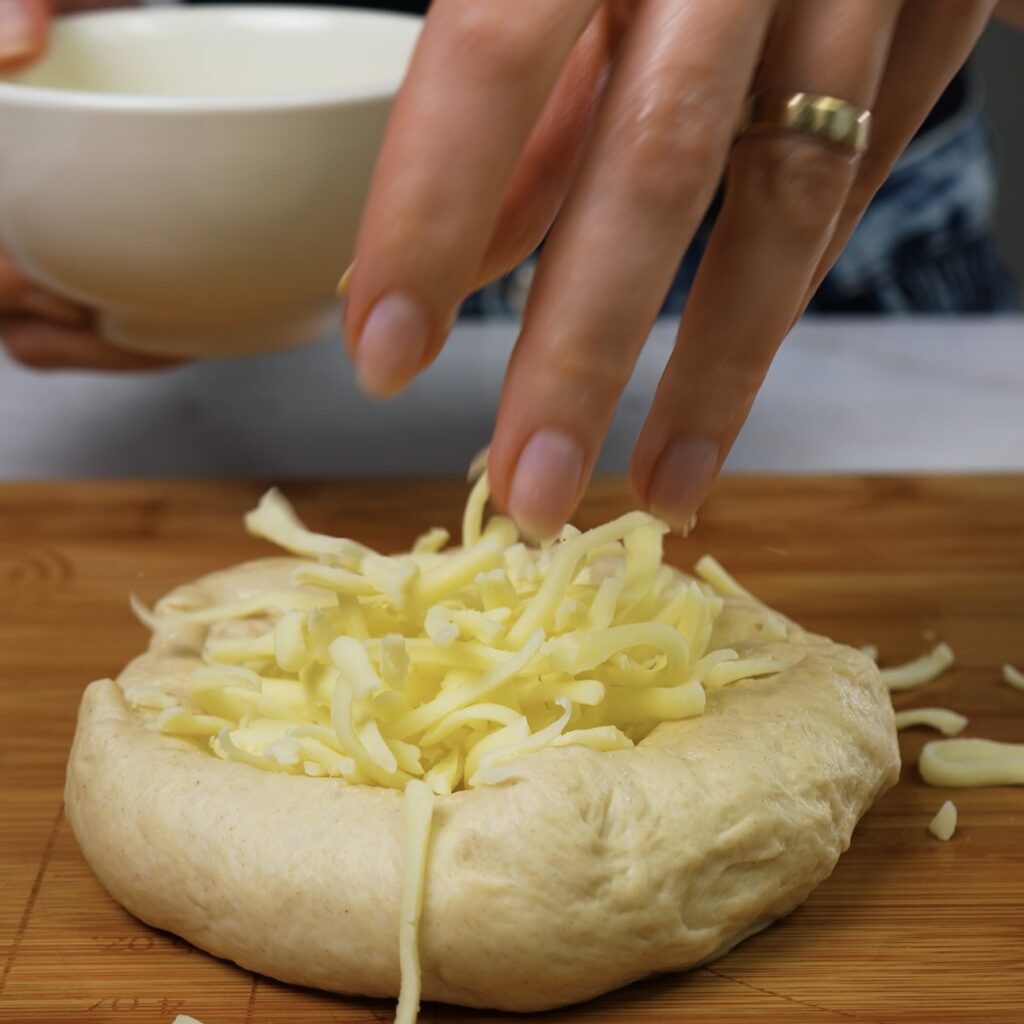 Placing grated mozzarella cheese in the centre of the dough.