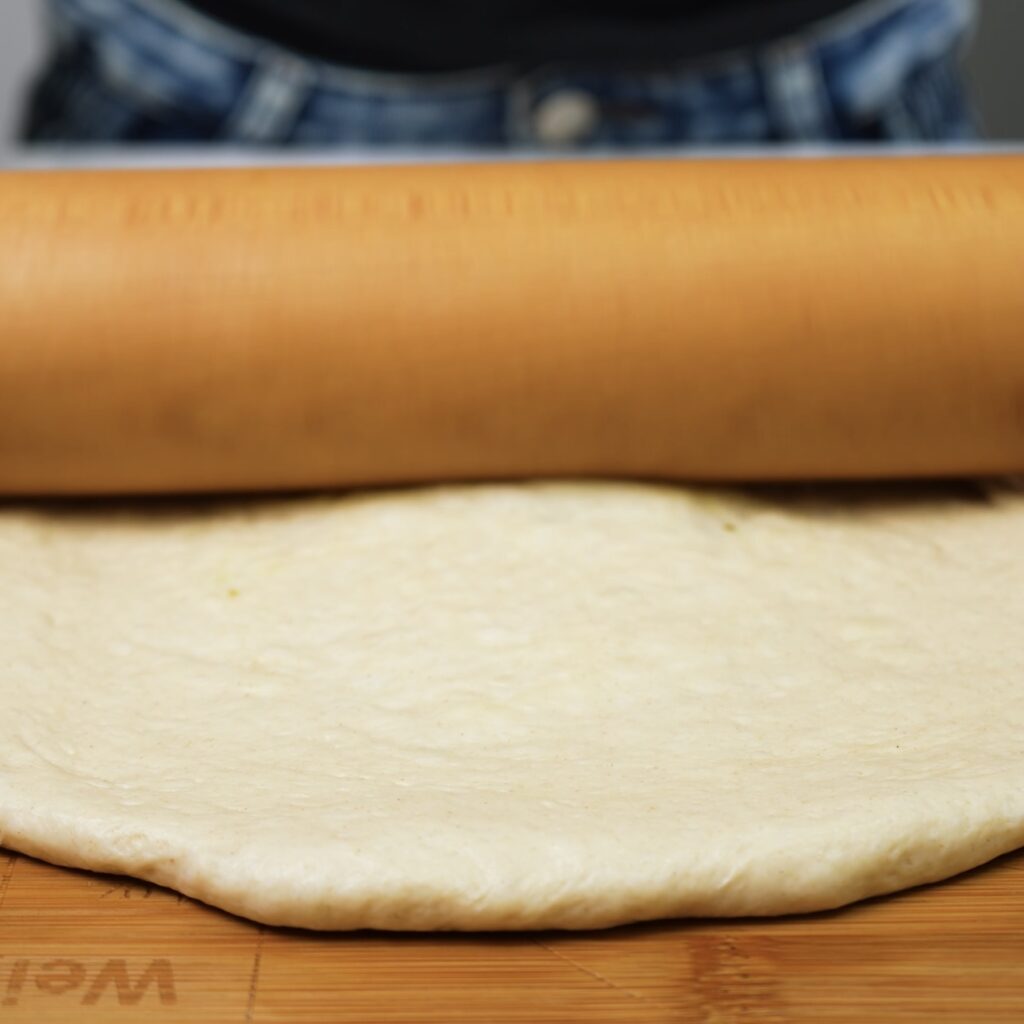 Rolling the dough into a flat circle.