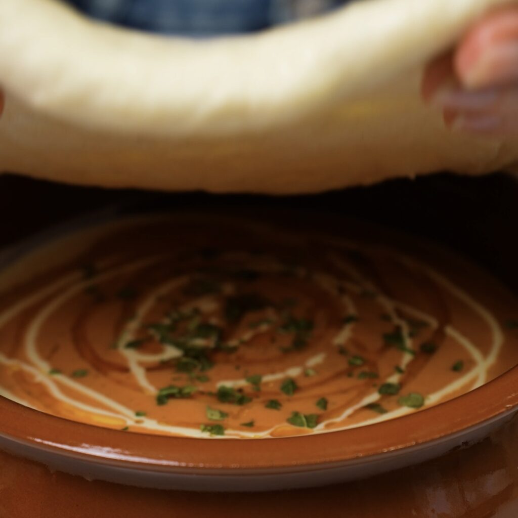 Covering the soup bowl with rolled dough.