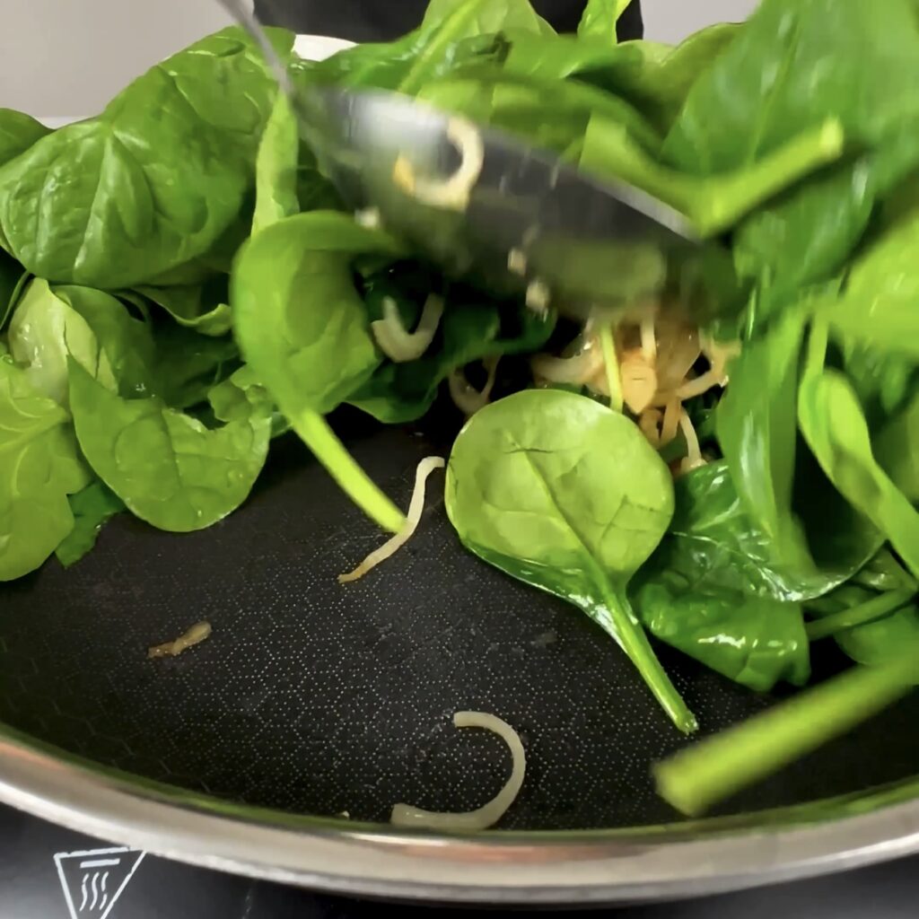 Fresh spinach wilting in a frying pan