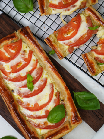 Golden Caprese tarts featuring flaky puff pastry, layered with juicy tomatoes, mozzarella, and fresh basil.