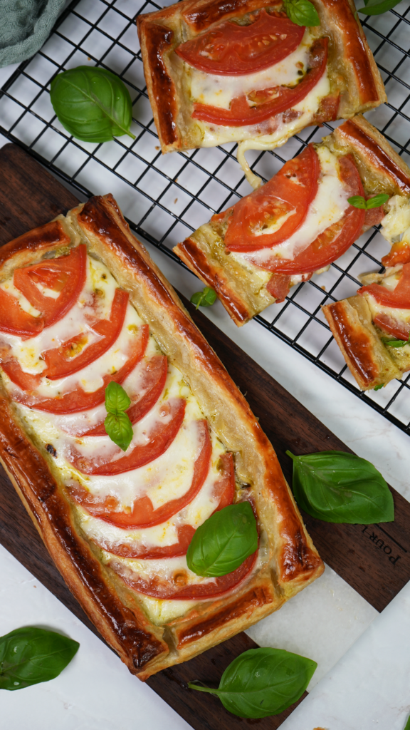 Golden Caprese tarts featuring flaky puff pastry, layered with juicy tomatoes, mozzarella, and fresh basil.