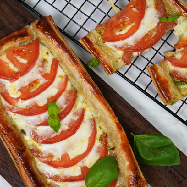 Golden Caprese tarts featuring flaky puff pastry, layered with juicy tomatoes, mozzarella, and fresh basil.