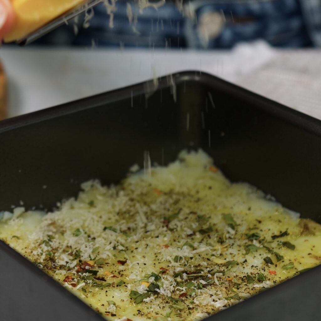 Pressed and seasoned potatoes in a greased cake tin, drizzled with olive oil.