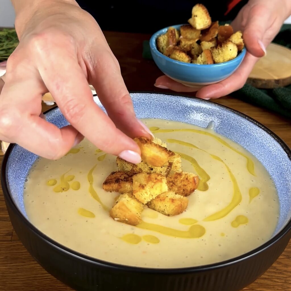 Adding croutons to a bowl of Roasted Parsnip Soup.