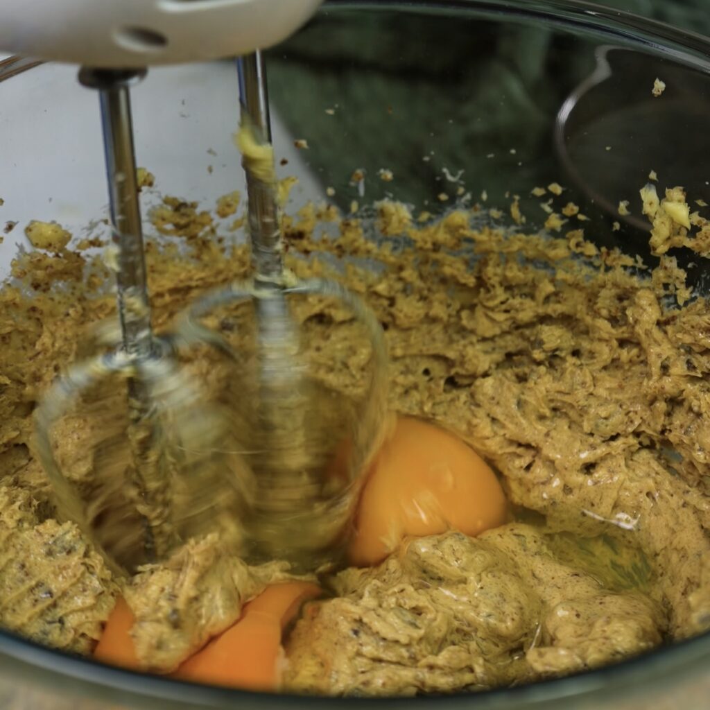 Whisking eggs with butter and sugar in a mixing bowl