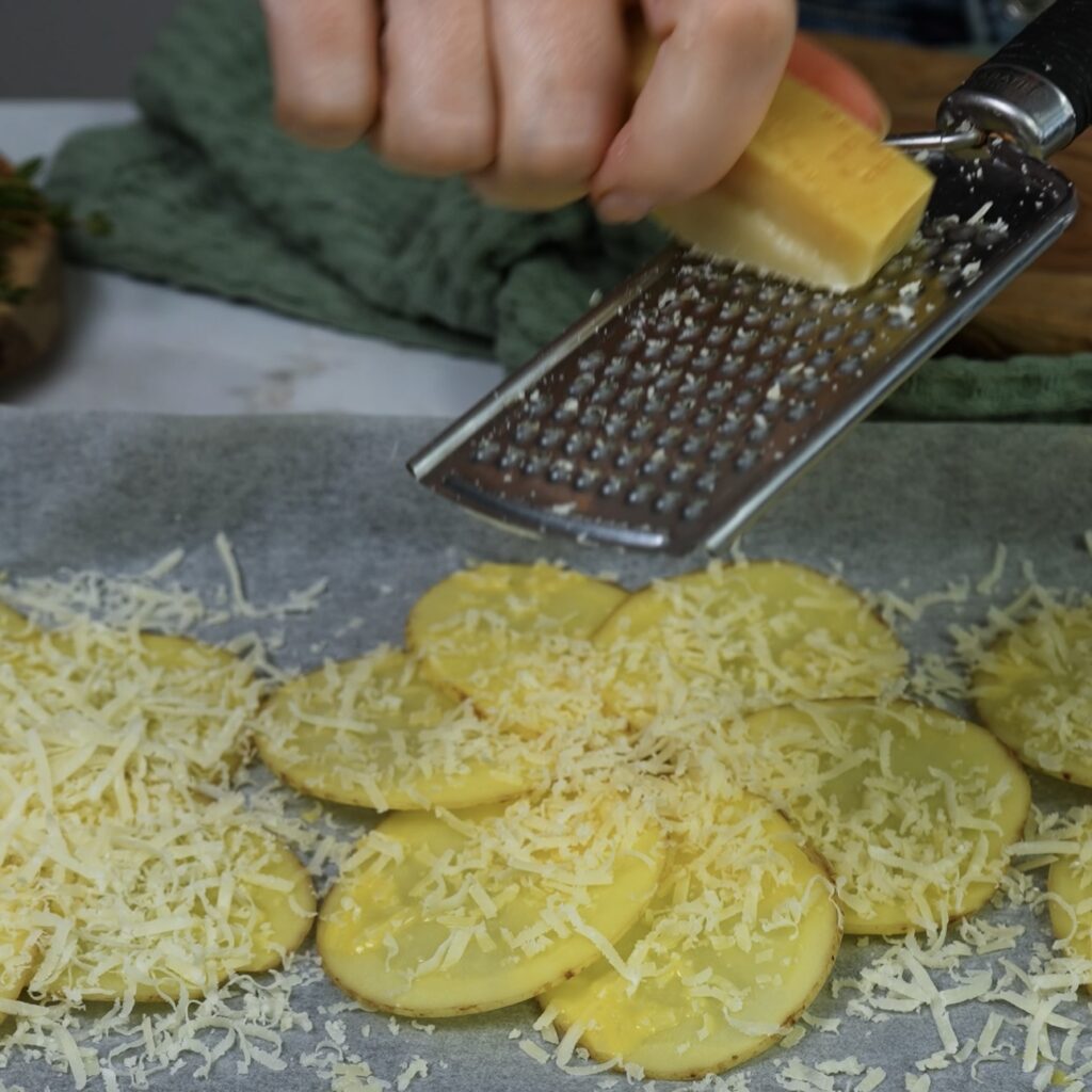 Potato flower shape topped with grated Parmesan cheese on a baking tray.