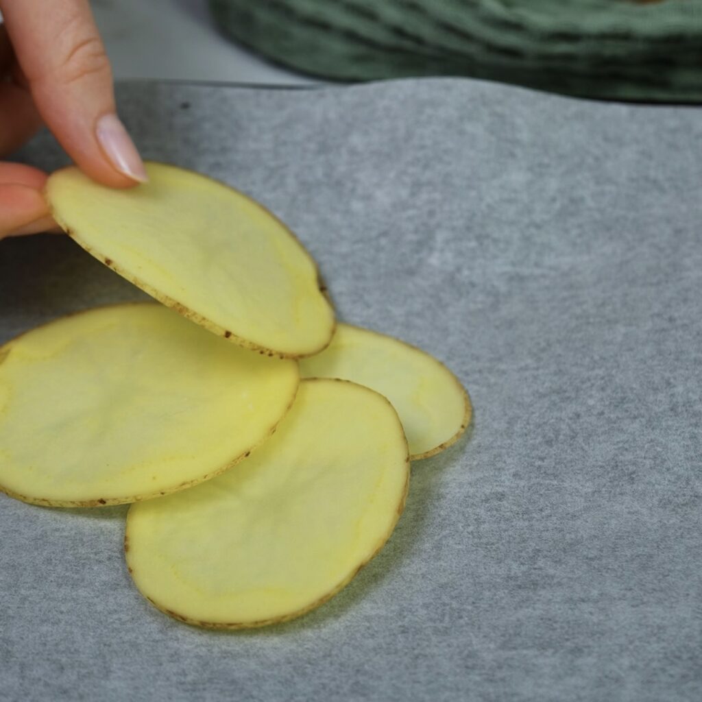 Potato slices partially arranged on a baking tray, preparing to form the base for Breakfast Potato Cups.