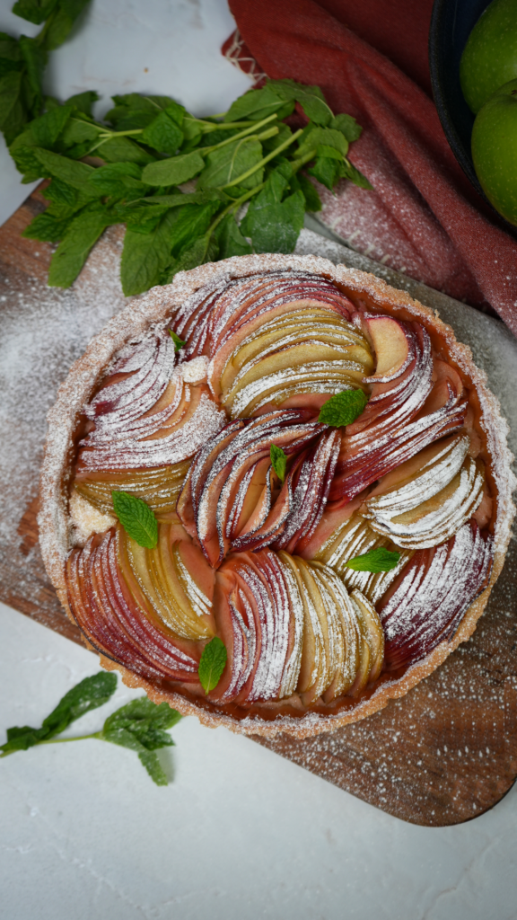 Whole Apple Bakewell Tart with golden crust and apple slices.