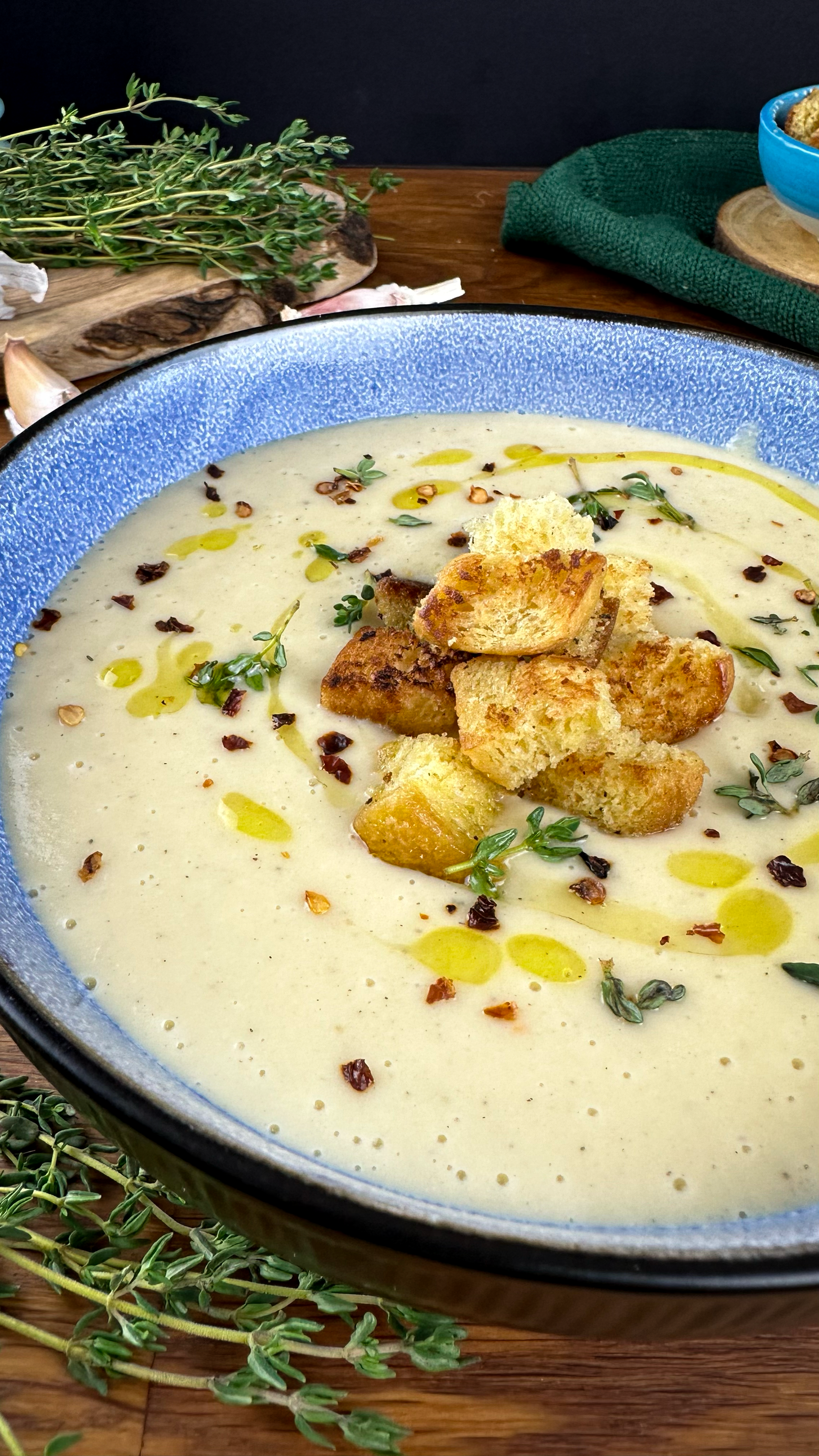 Bowl of creamy Roasted Parsnip Soup topped with croutons and fresh thyme.