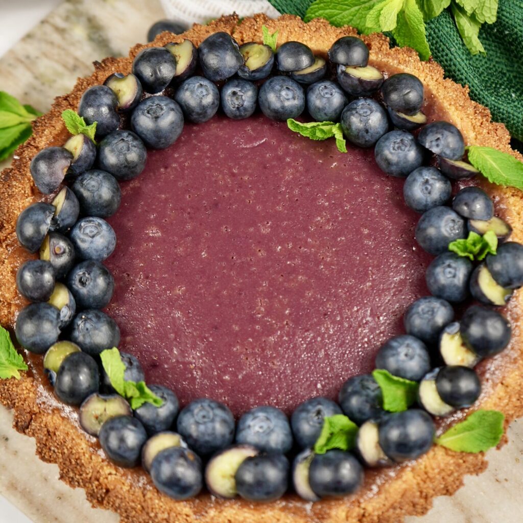 Overhead shot of a Berry Semolina Tart with blueberries and mint.