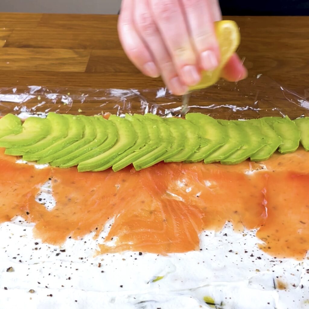 Drizzling lemon juice over salmon and avocado filling.