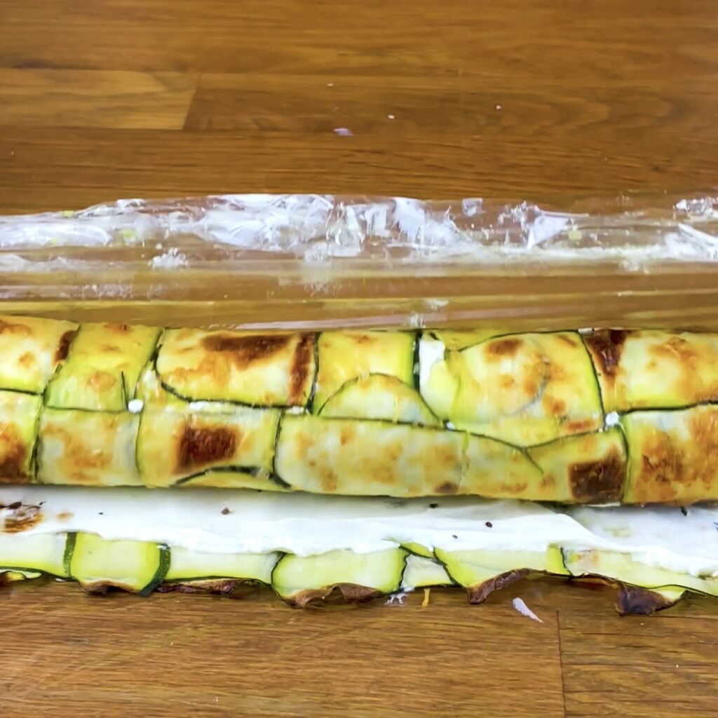 Rolling up the courgette salmon roll tightly.