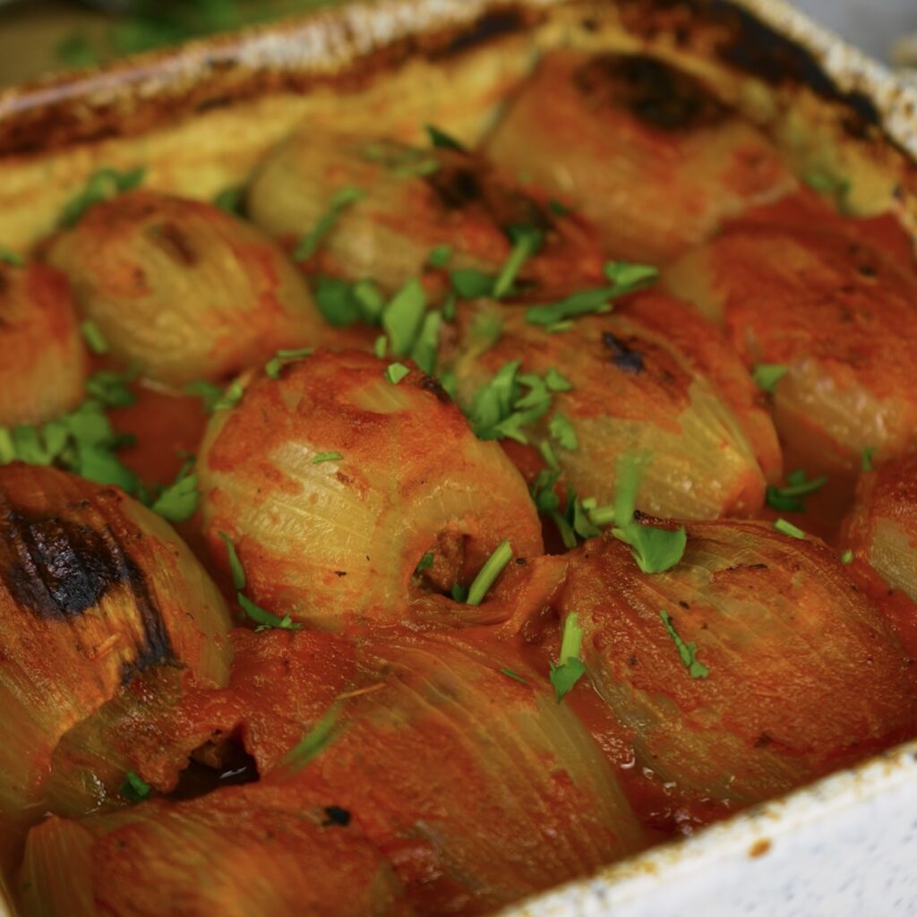 Baked stuffed onions with a golden top, garnished with fresh coriander.