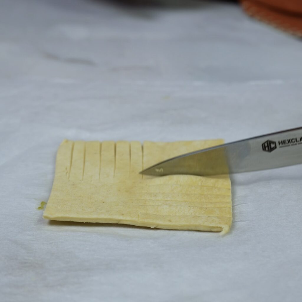 Making seven thin strips through the puff pastry.