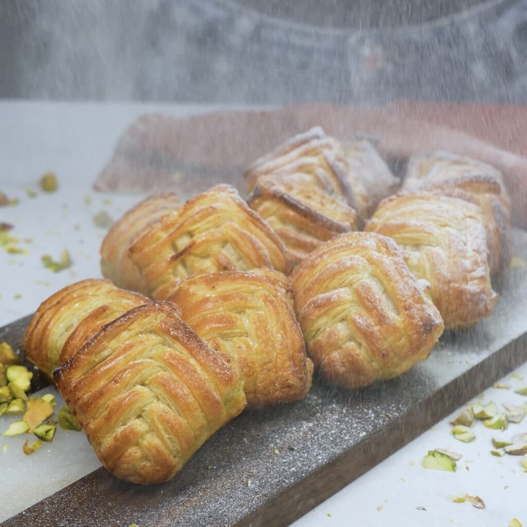 Dusting Pistachio Puffs with icing sugar.