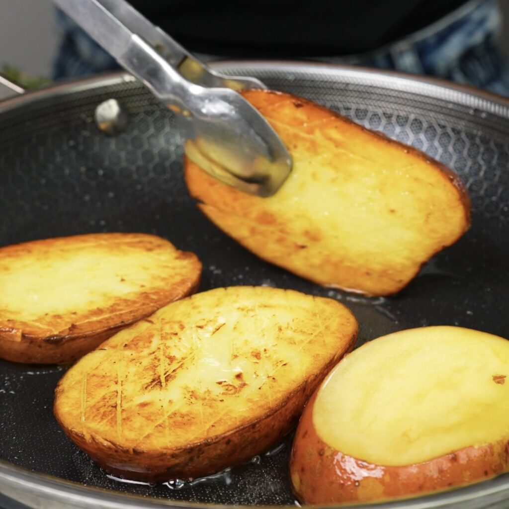 Flipping a golden-brown potato slice in a frying pan