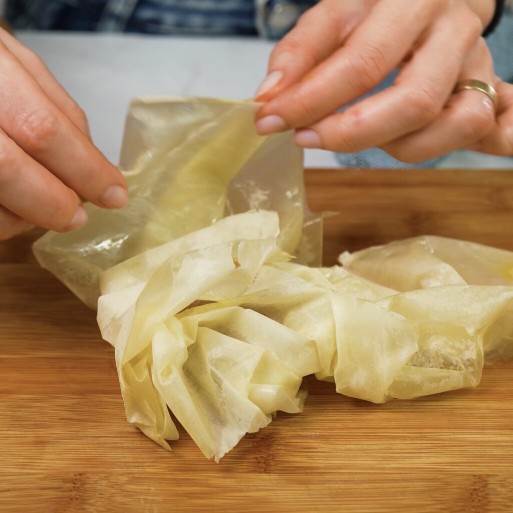 Folding filo pastry petals over pistachio paste to form a bun.