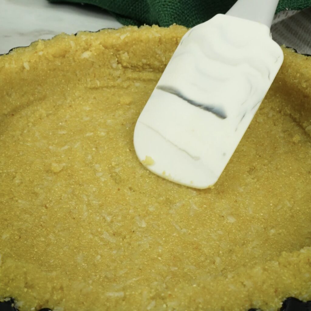 Pressing semolina crust mixture into a tart tin.