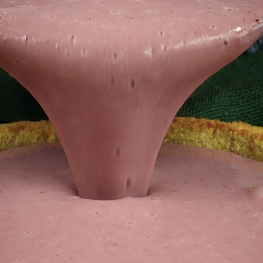 Pouring berry filling into the prepared tart crust.