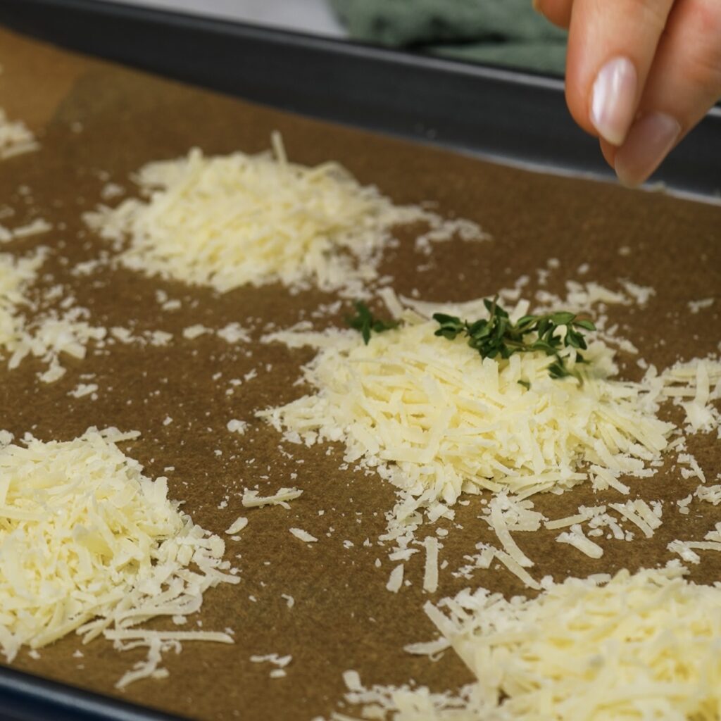 Grated Parmesan topped with fresh thyme on a baking tray.