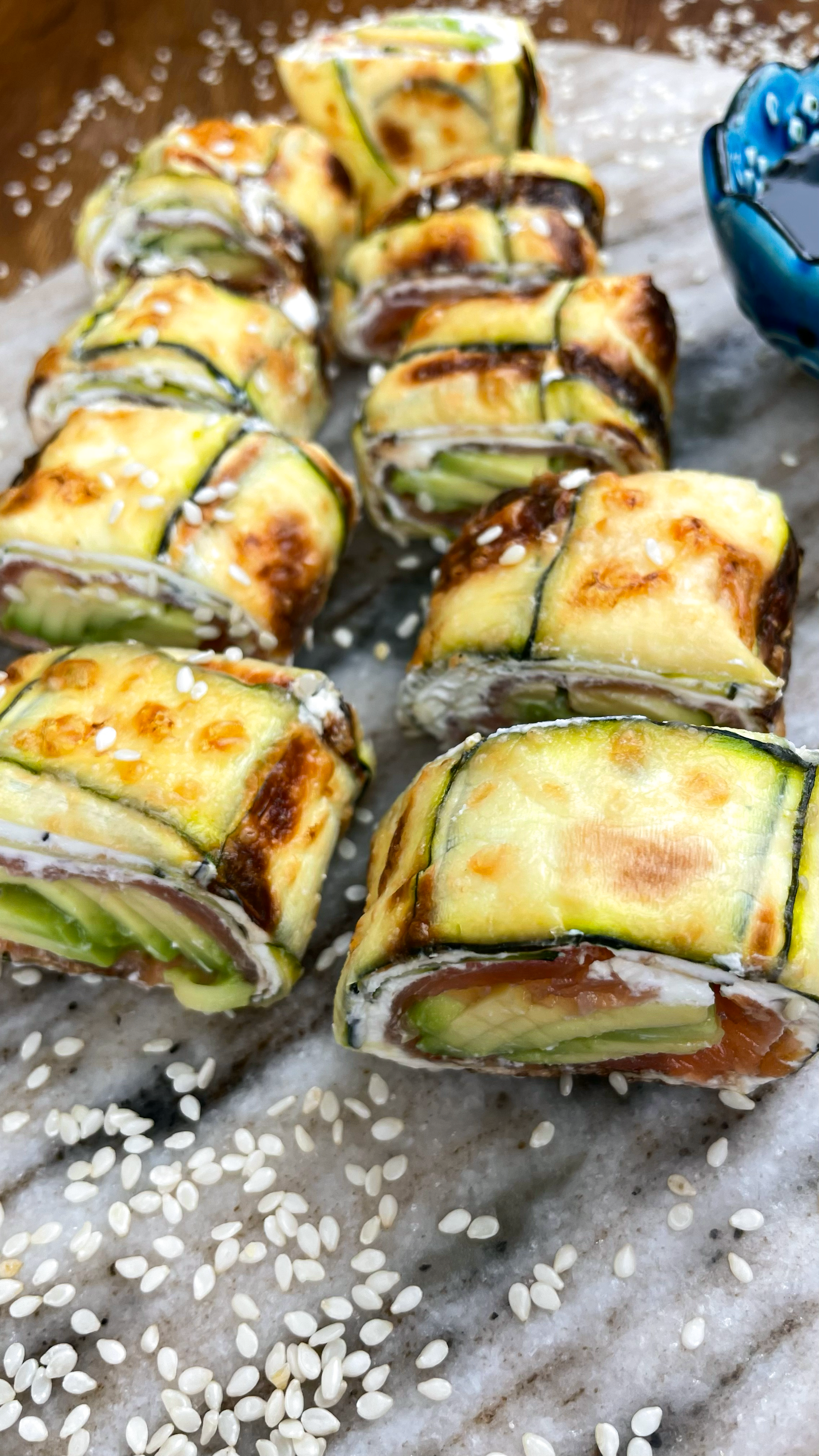 Sliced Courgette Salmon Roll with avocado, cream cheese, and soy sauce.