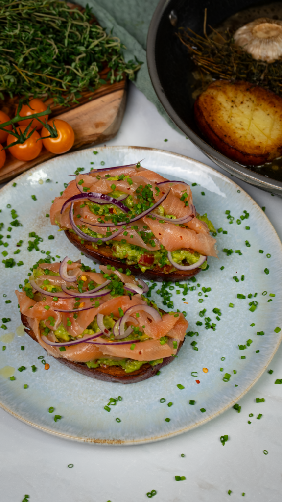 Potato toast topped with smashed avocado, smoked salmon, red onion slices, and fresh chives