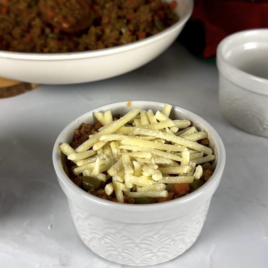 Layers of beef filling and cheese in a greased ramekin.