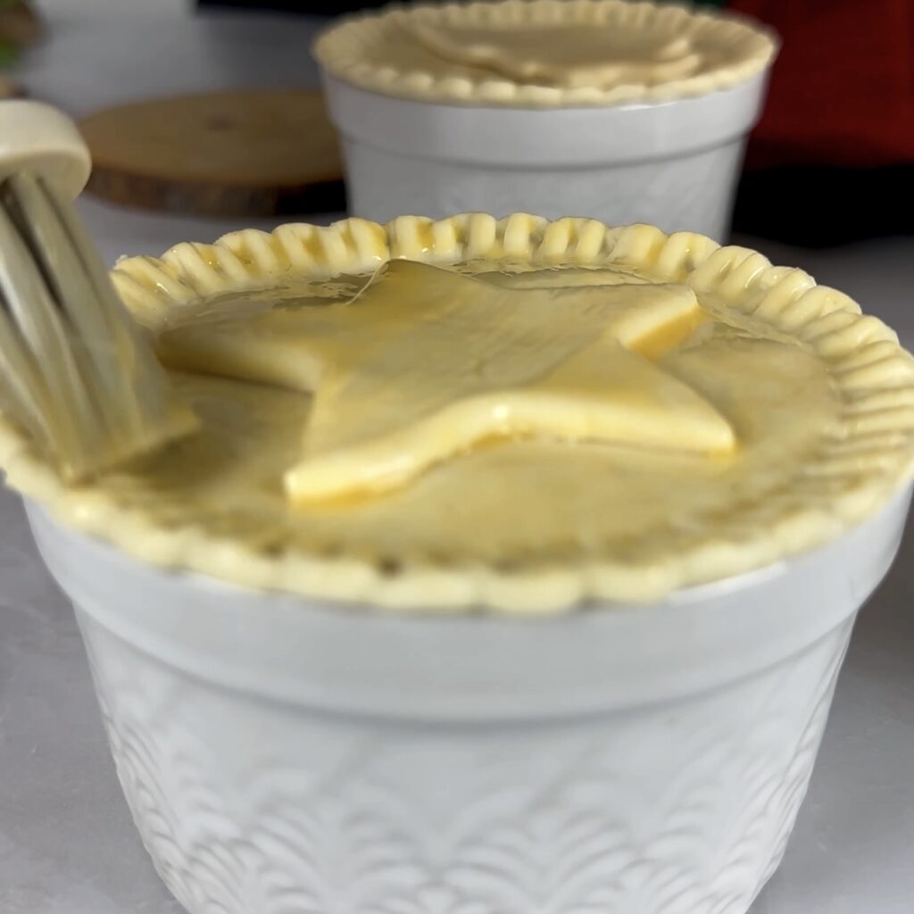 Puff pastry being brushed with egg wash using a pastry brush.