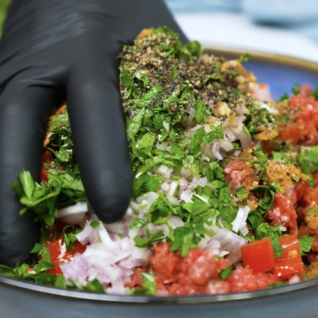 Mixing minced meat, tomatoes, and spices for the potato filling.