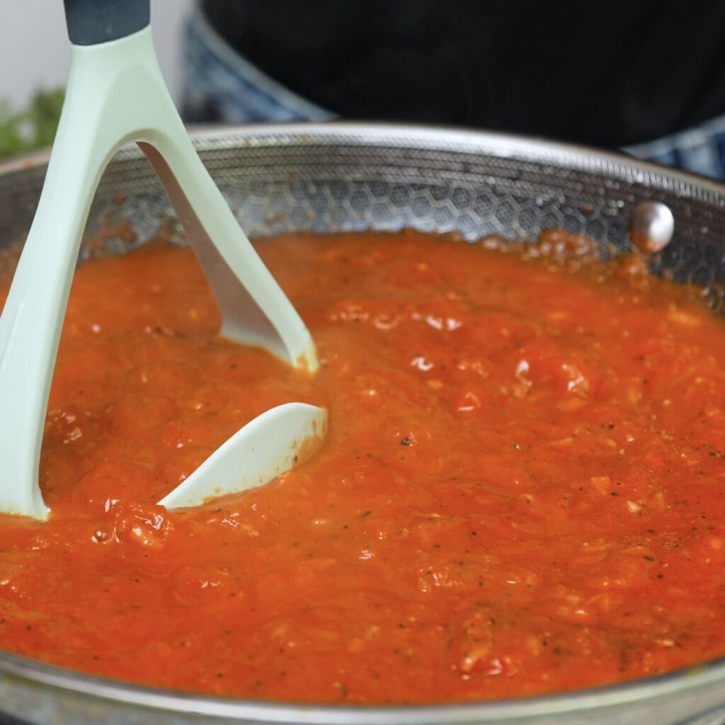 Preparing the rich homemade tomato sauce for stuffed potato boats.