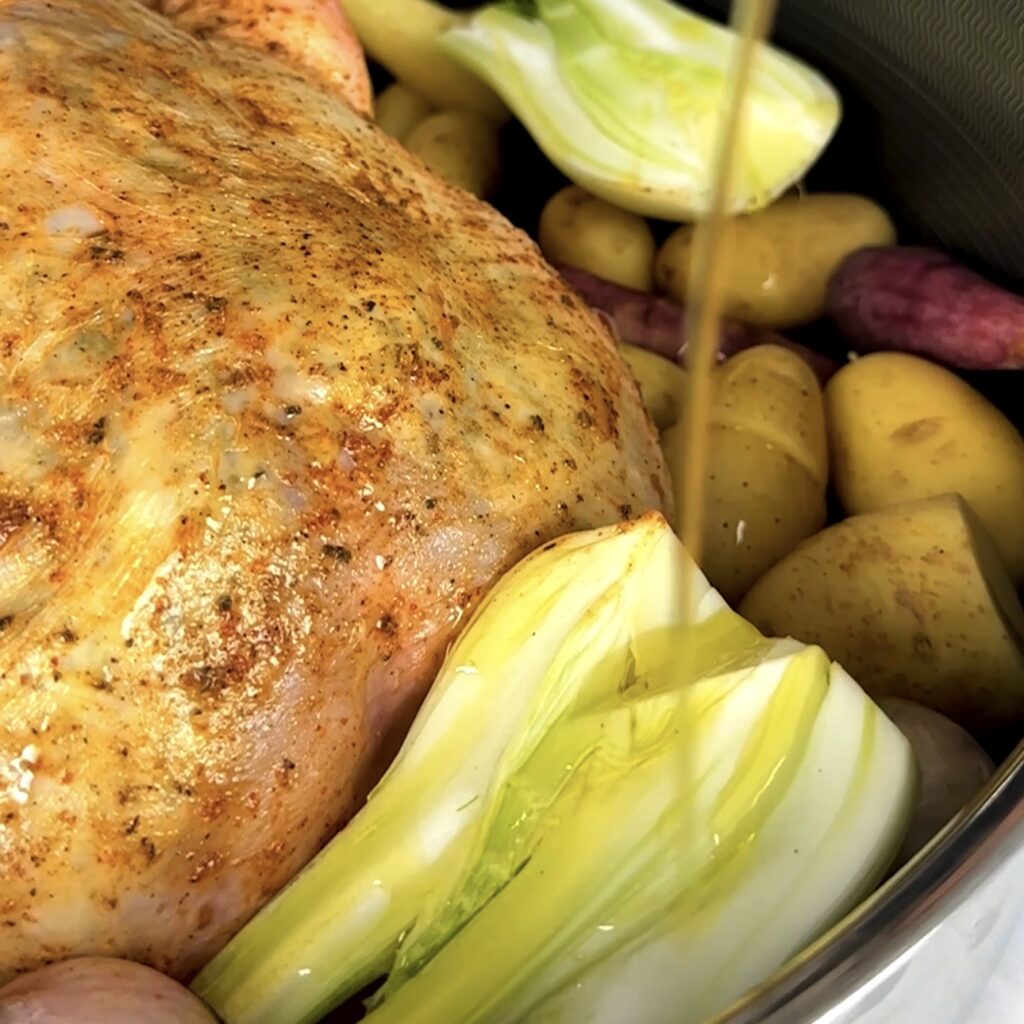 Drizzling olive oil over the vegetables in the roasting pan.