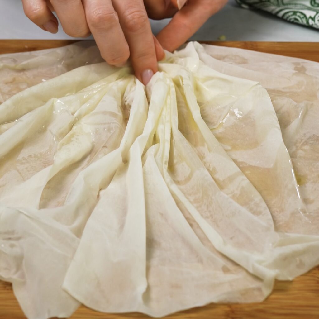 Pinching the centre of filo pastry to create an accordion crinkle.