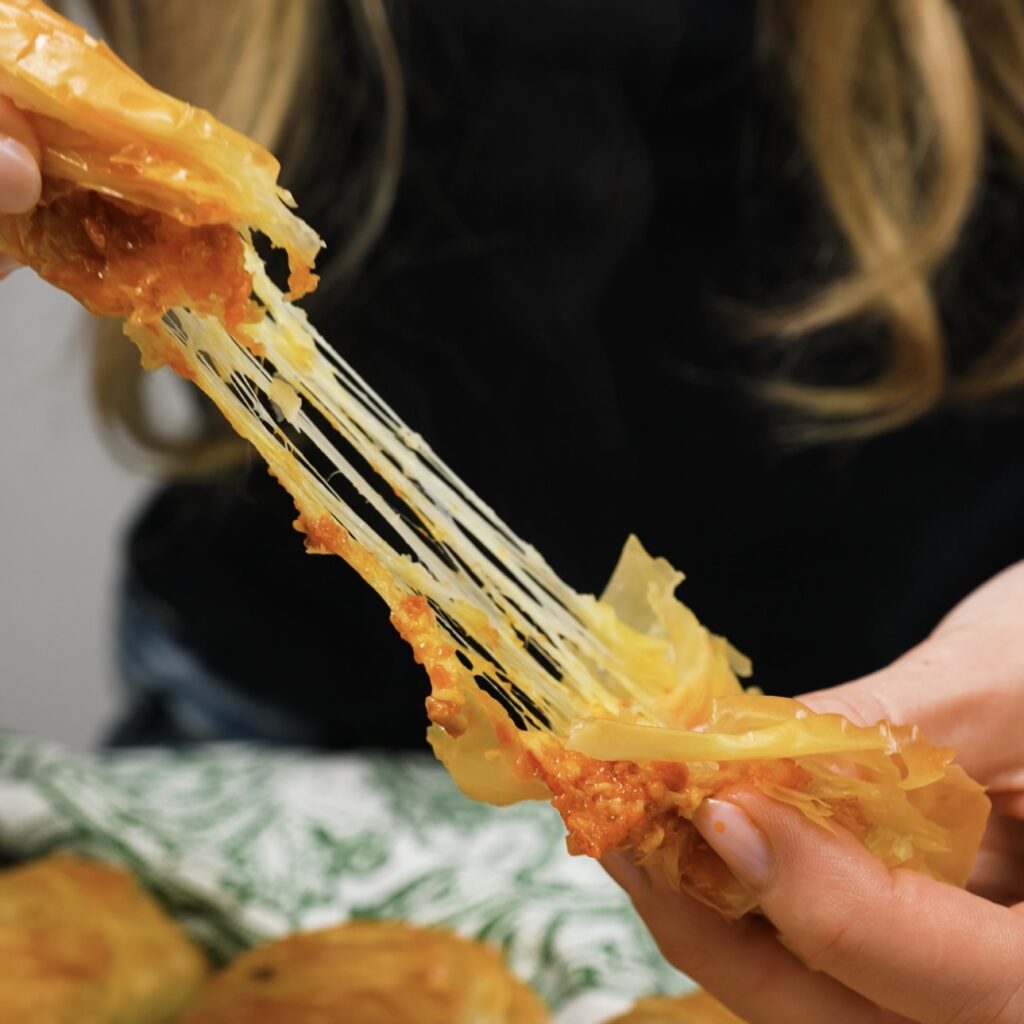 Cheese stretching from a freshly baked pesto mozzarella filo bun