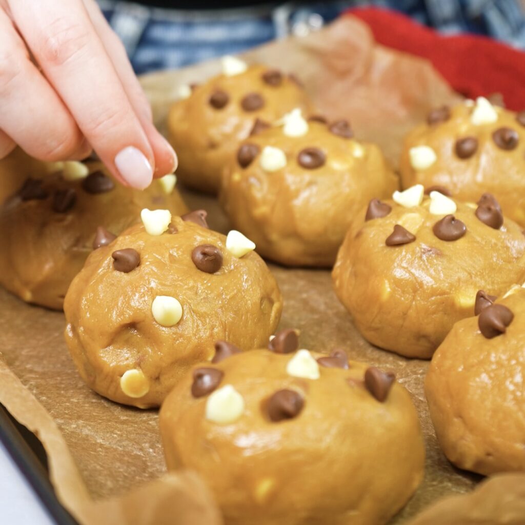 Pressing chocolate chips onto the tops of cookie dough balls before baking.