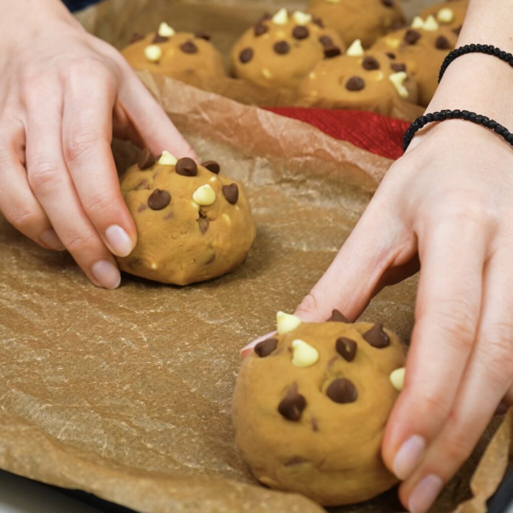 Placing cookie dough balls on a baking tray, leaving space between each one.