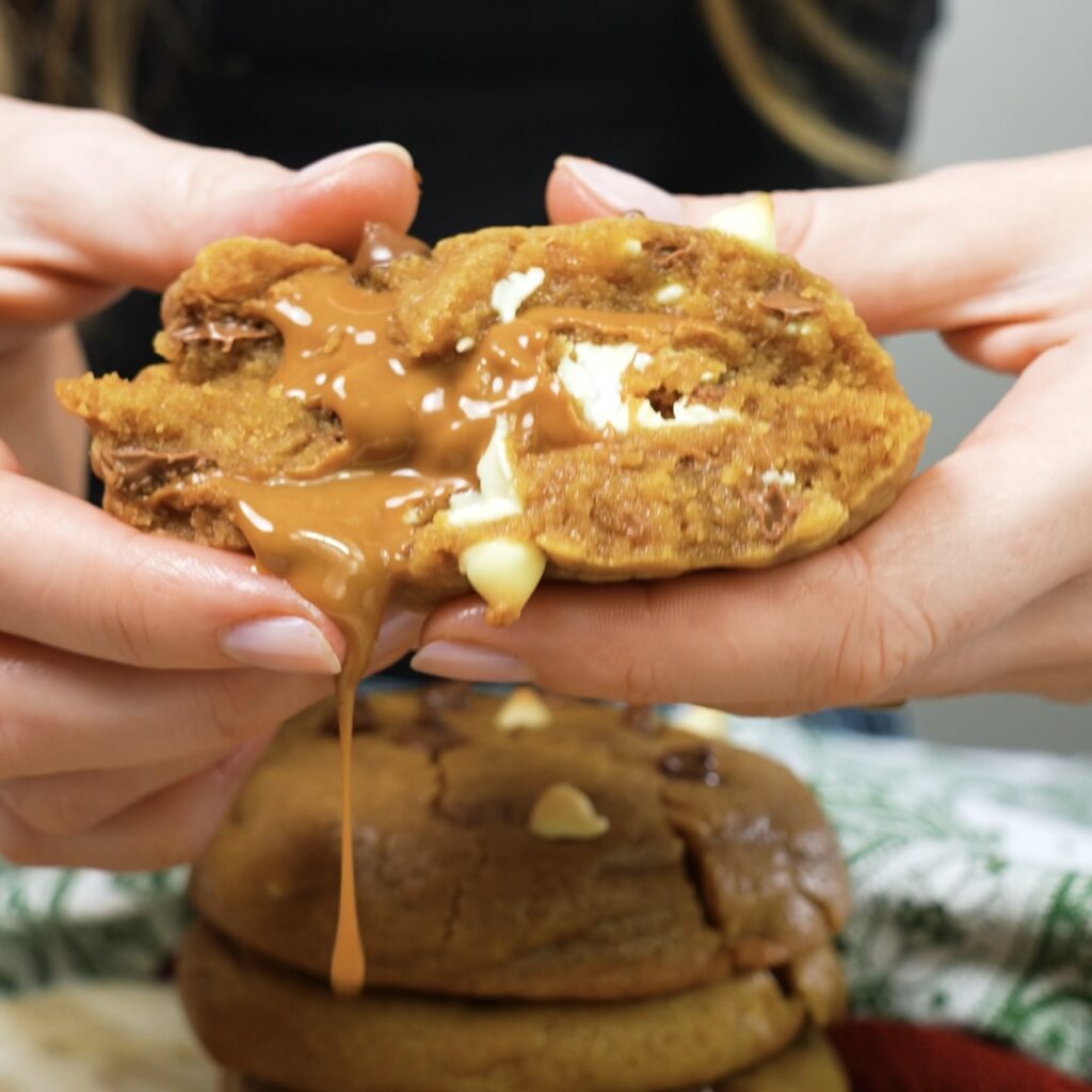 A cookie broken in half, revealing the gooey Biscoff filling inside.