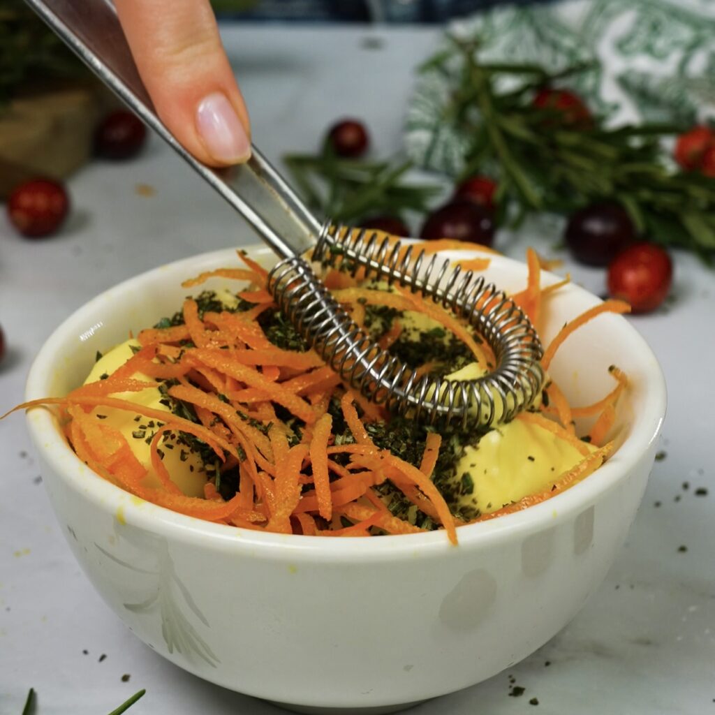 Mixing softened butter with rosemary and orange zest for infused butter