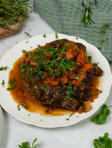 Braised beef shanks with aromatic herbs and vegetables in a rich sauce.