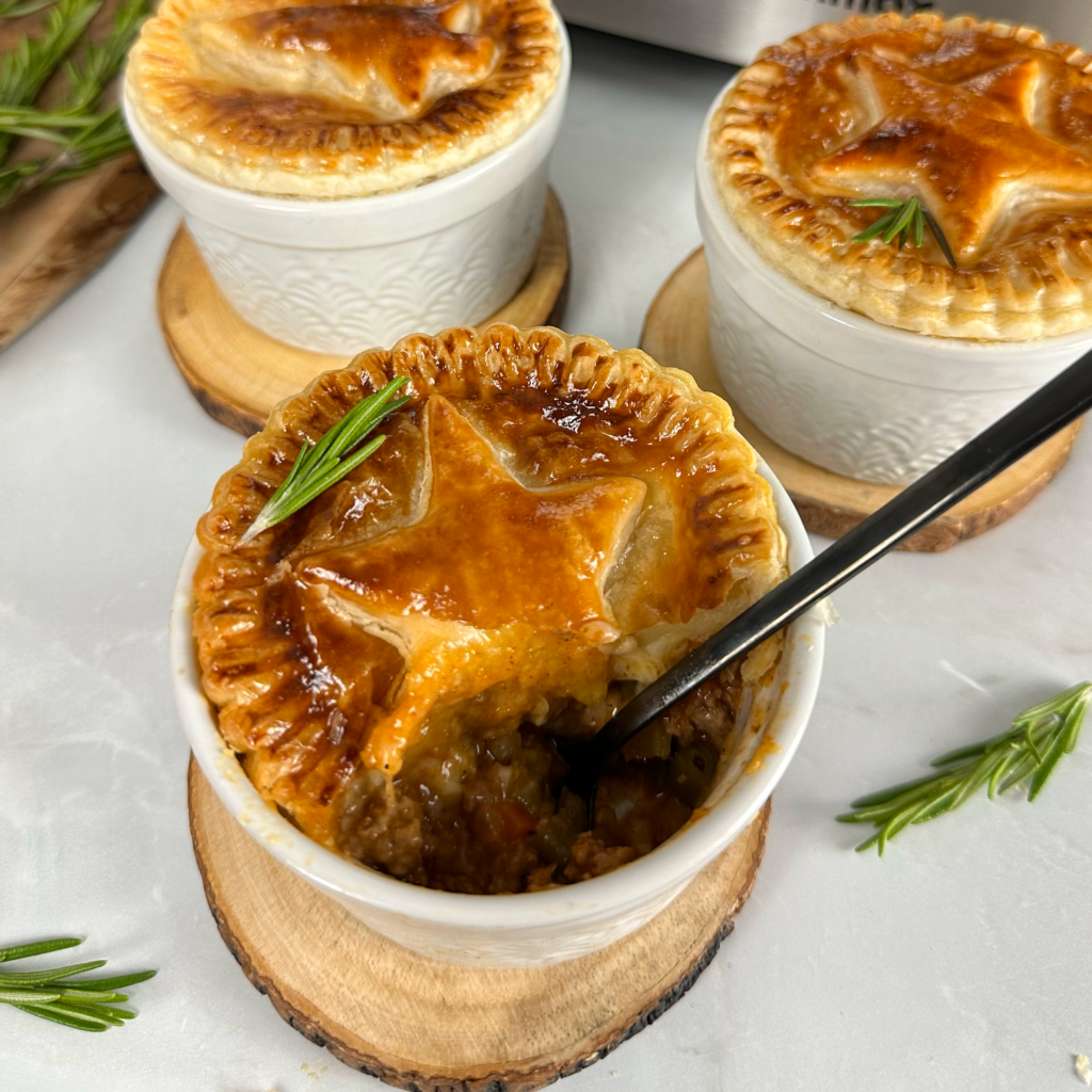 A spoon scooping filling from an Individual Christmas Pie with golden puff pastry.