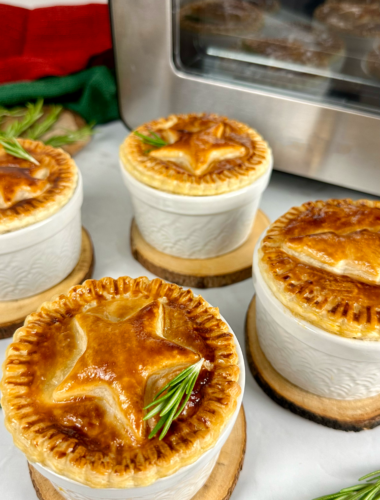 Golden Individual Christmas Pies topped with festive puff pastry decorations.