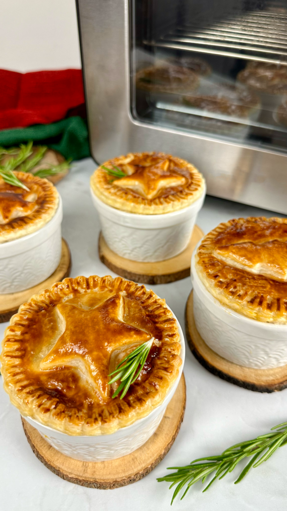 Golden Individual Christmas Pies topped with festive puff pastry decorations.