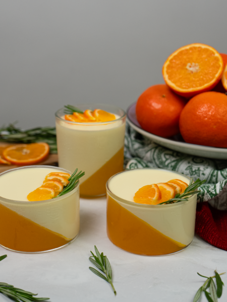 Layered mandarin panna cotta dessert in serving glasses.