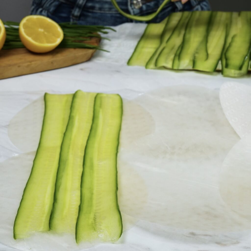 Arranging cucumber slices on a rice paper for a Rice Paper Cucumber Roll.